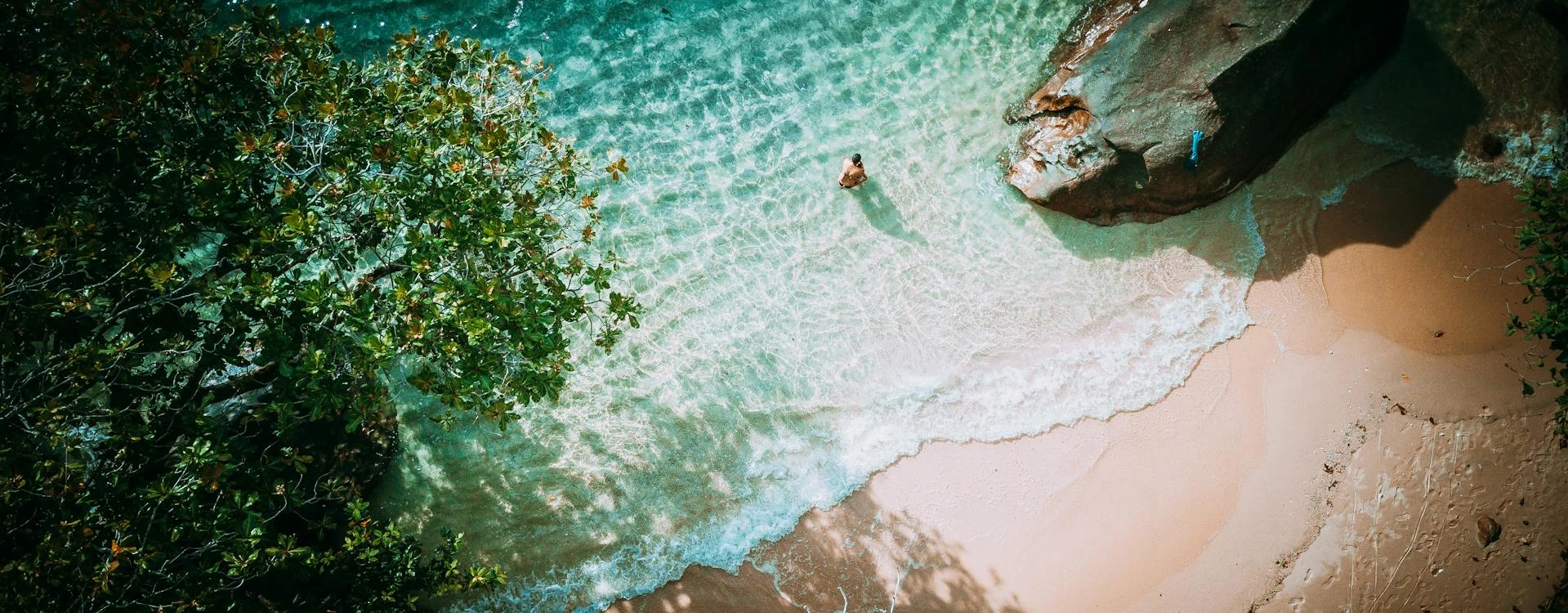 Person bathing on a tropical beach with white sand and crystal clear waters