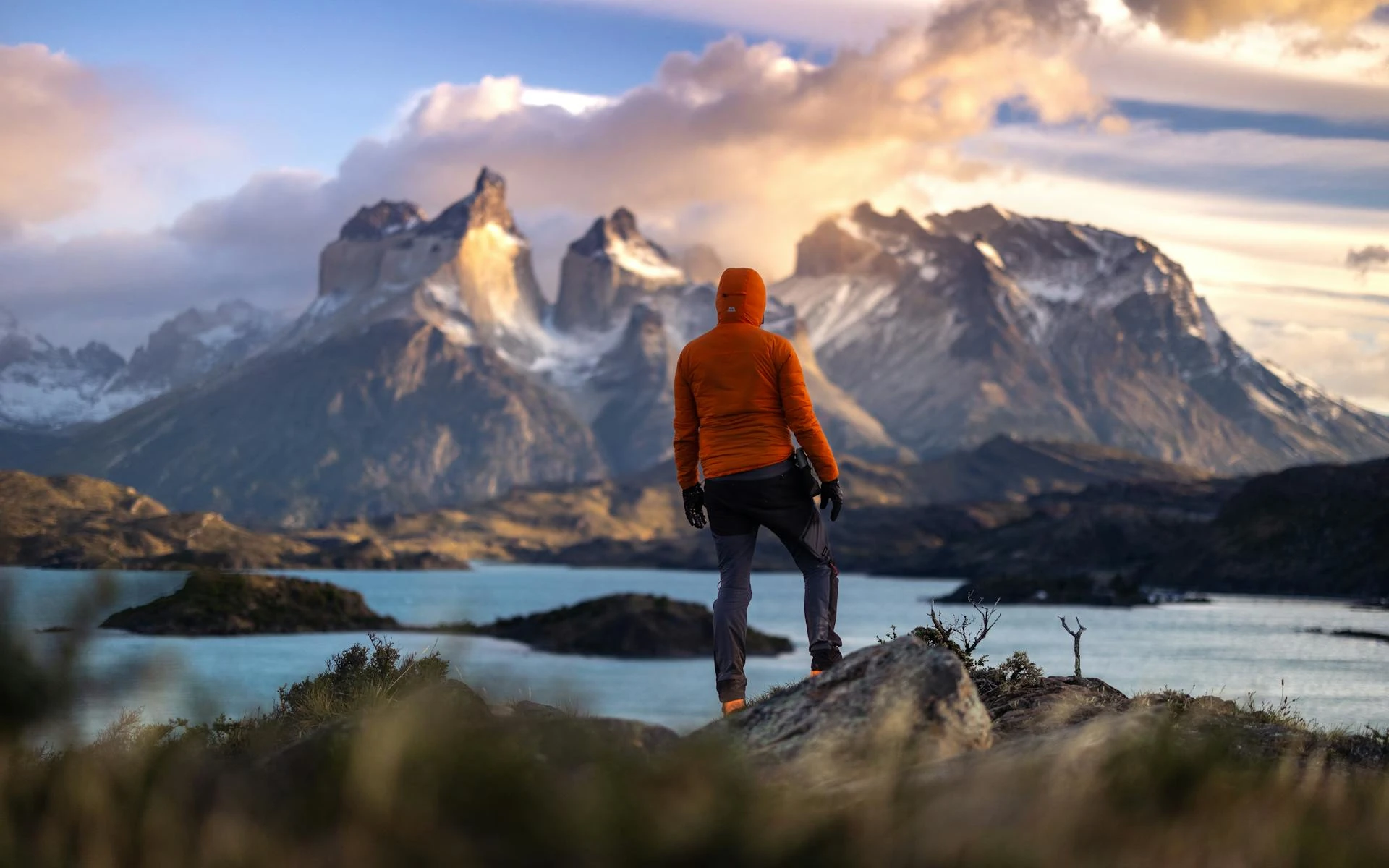 Male hiker in jacket admiring the snow-capped Torres del Paine mountains in Patagonia, Chile.