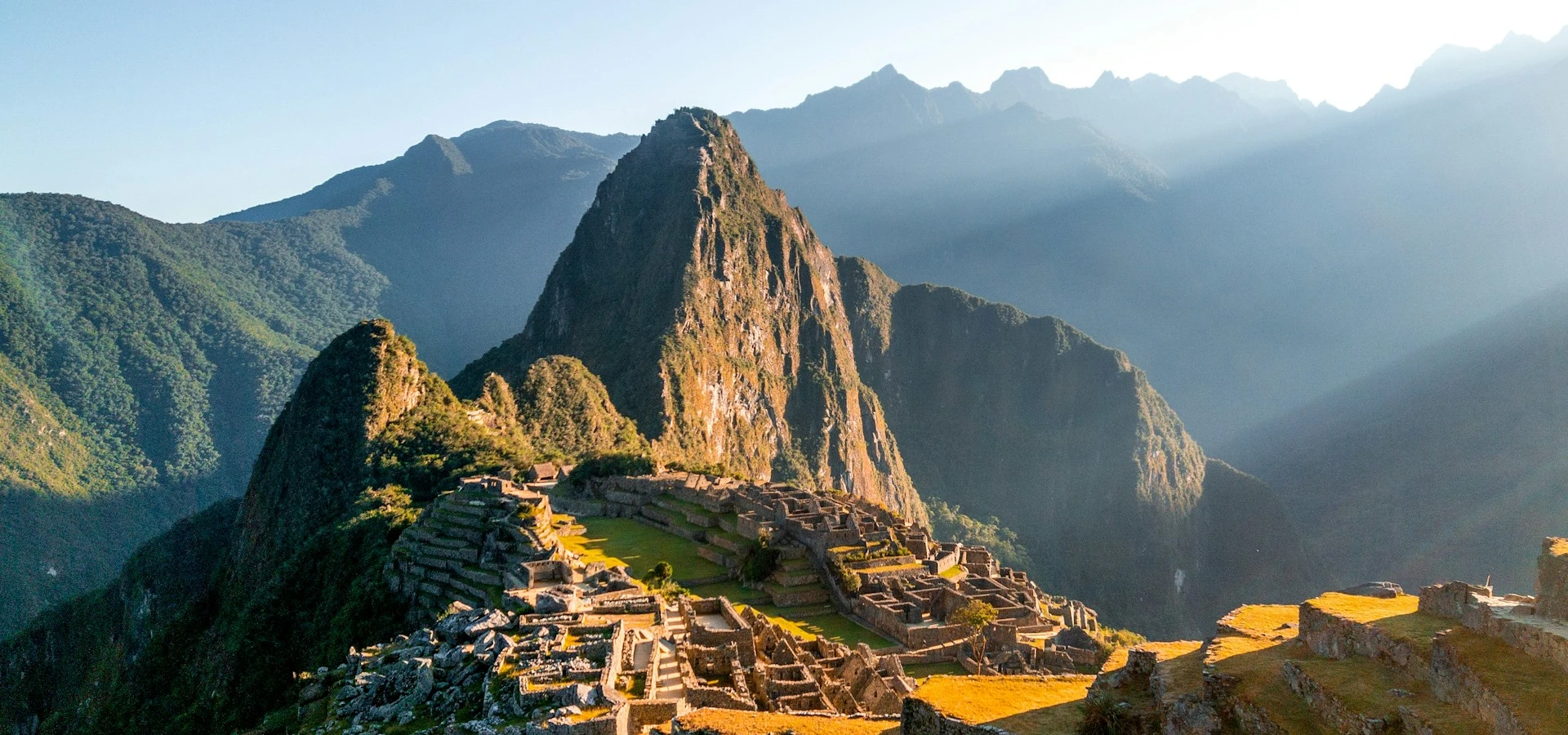 A view of the sacred city of Machu Picchu on a clear day, with the mountains on the horizon clearly visible.