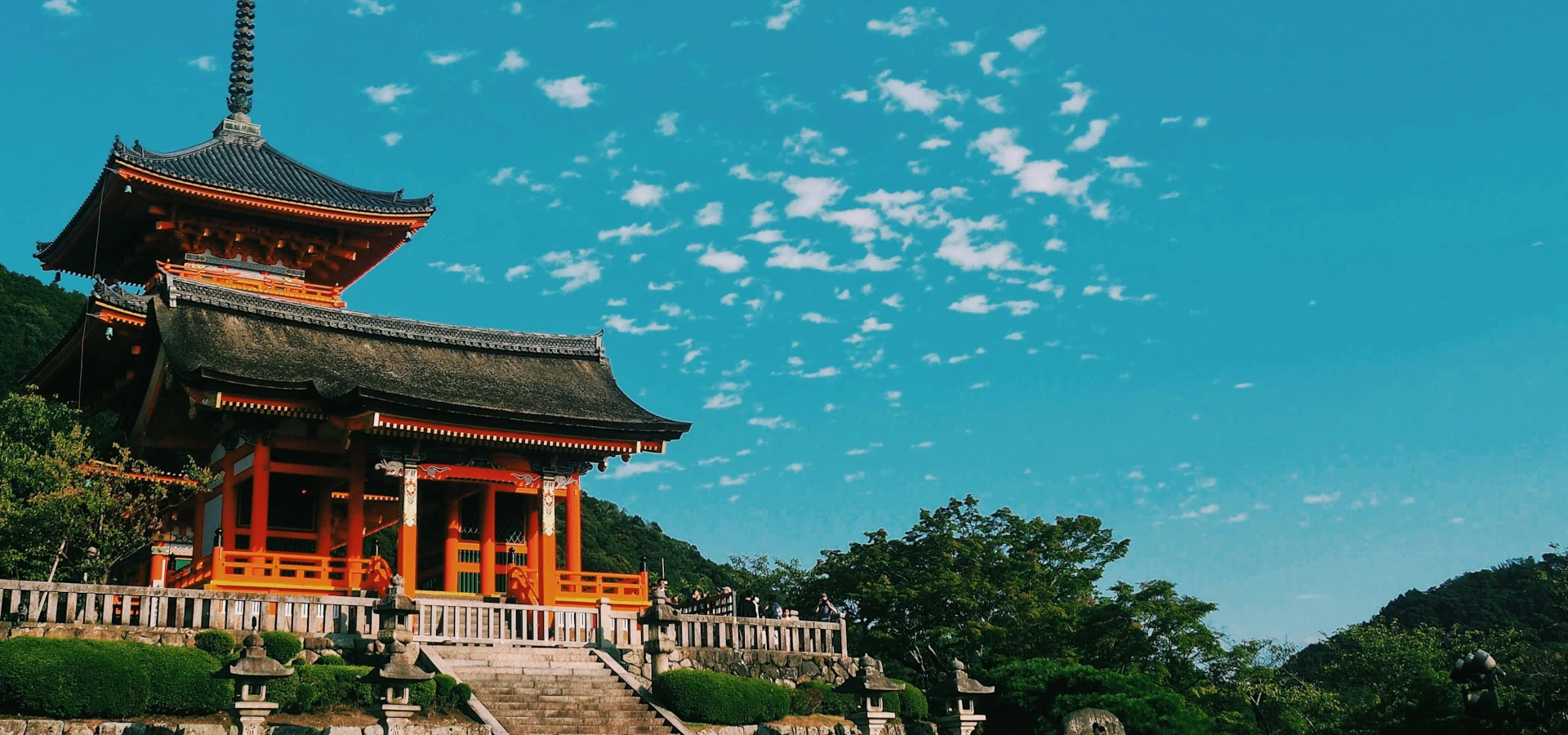 A view of a red ancient temple, surrounded by lush greenery and vibrant culture.