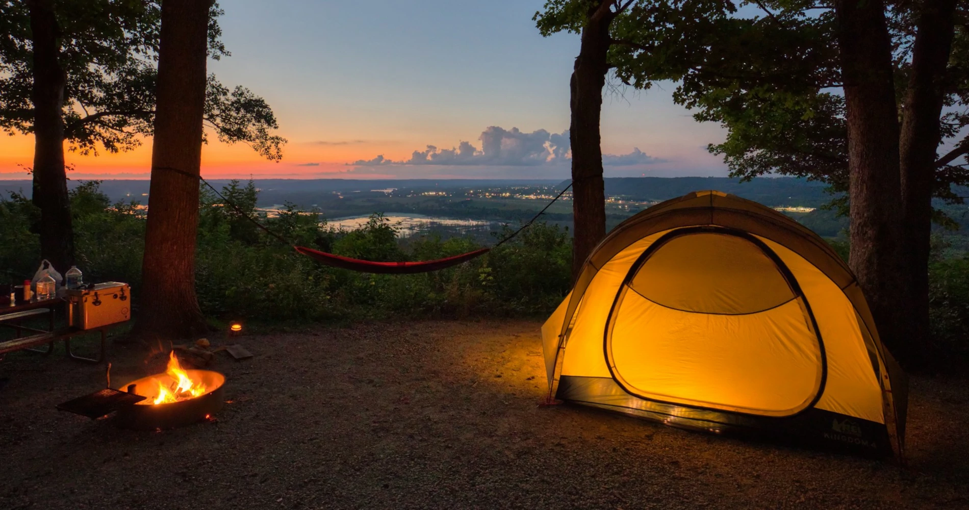 A tent set up in the woods at sunset A tent set up in the woods at sunset