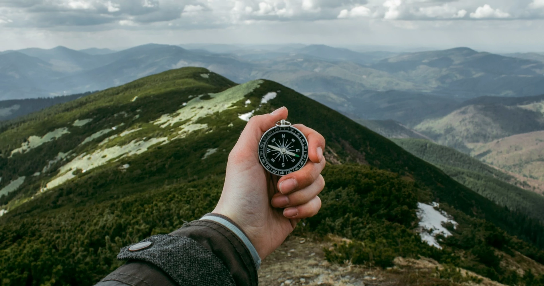 Person holding a compass on the mountains Person holding a compass on the mountains