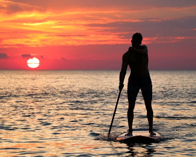 A man riding a paddleboard during the sunset A man riding a paddleboard during the sunset