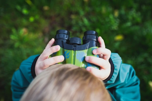 Boy in blue shirt holding binoculars Boy in blue shirt holding binoculars