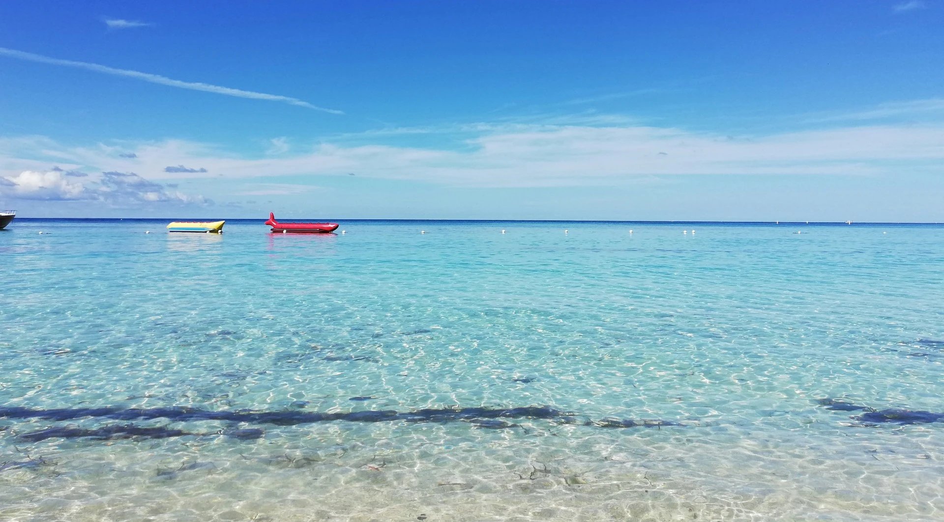 Beach with clear turquoise waters, with inflatables for children or tourists a short distance away