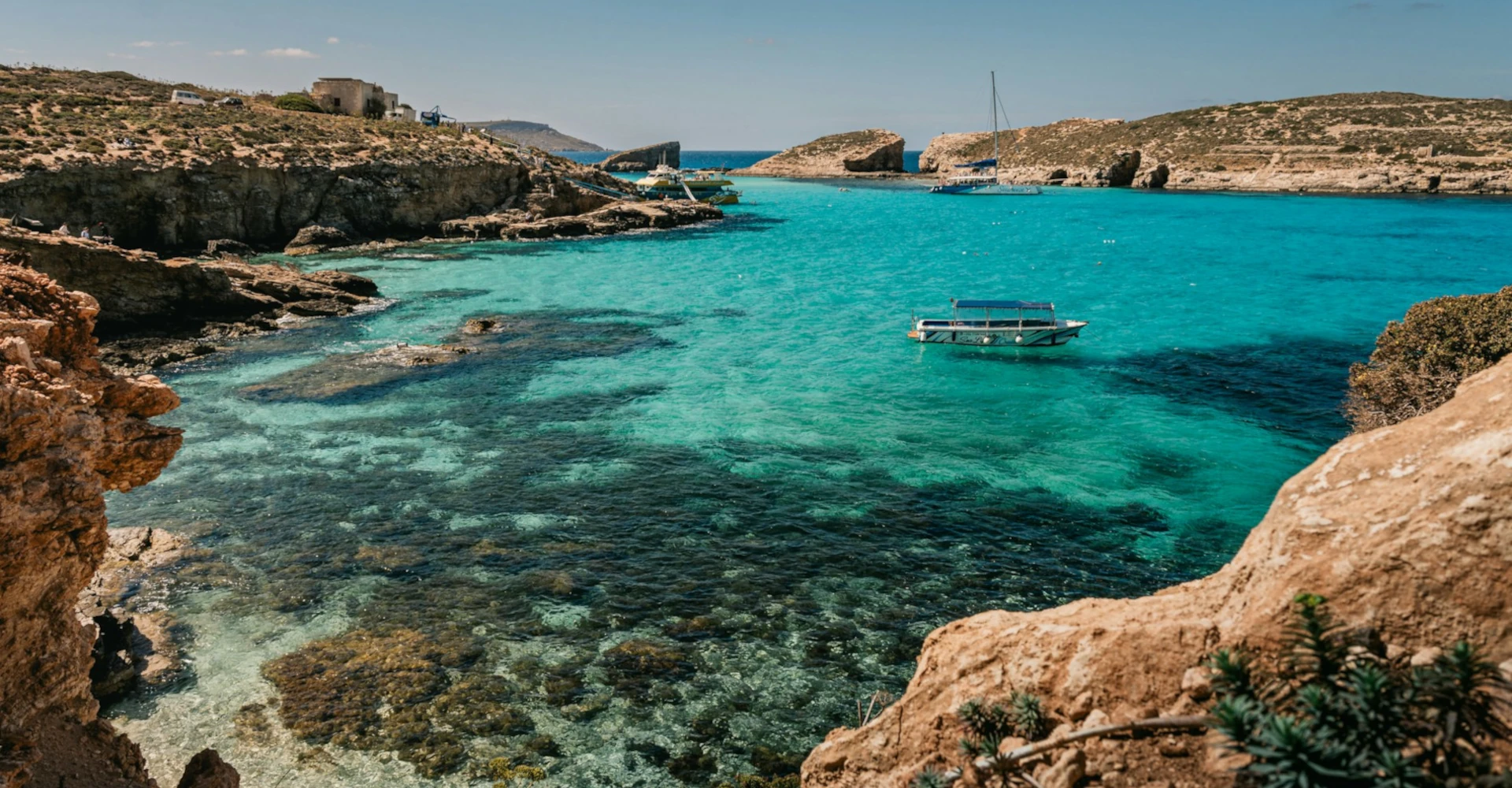 Crystal-clear turquoise waters of the Blue Lagoon in Malta with a small boat floating peacefully and no people in sight