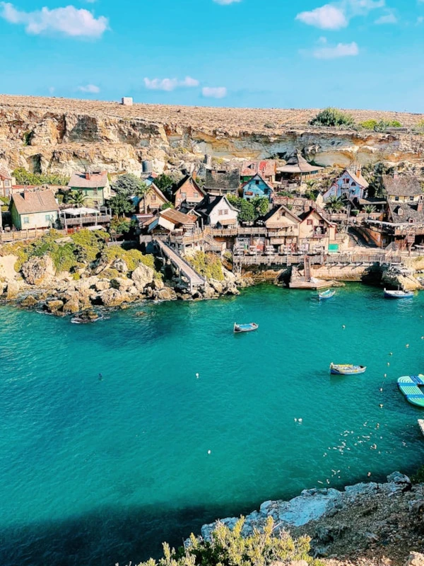 View of Popeye Village in Malta from above, with colorful buildings and vivid blue Mediterranean waters.