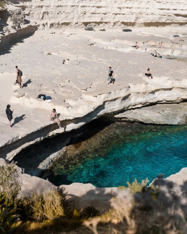 White rocky cliffs and crystal-clear blue water at St. Peter’s Pool, Malta’s popular cliff-jumping spot.