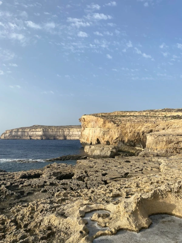 Dramatic coastal cliffs of Gozo, Malta, under a bright blue sky on a sunny day.