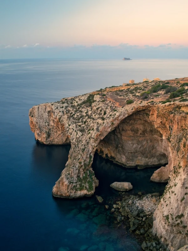 Aerial view of the Blue Grotto sea caves in Malta during a warm, golden sunset.
