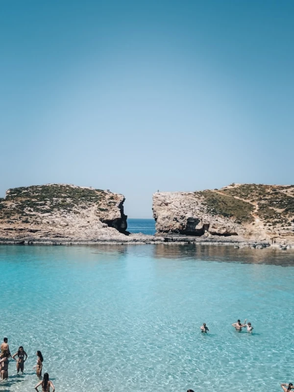 Almost empty Blue Lagoon in Comino, Malta, with crystal-clear turquoise waters, calm seas, and surrounding rocky coastline under a sunny sky