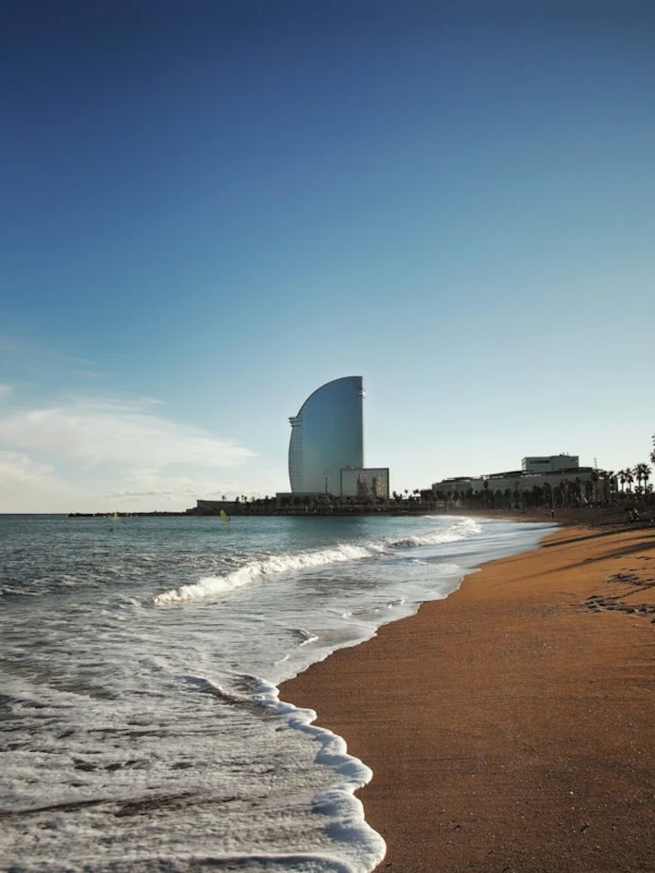 A calm and sunny beach with a big hotel on the background