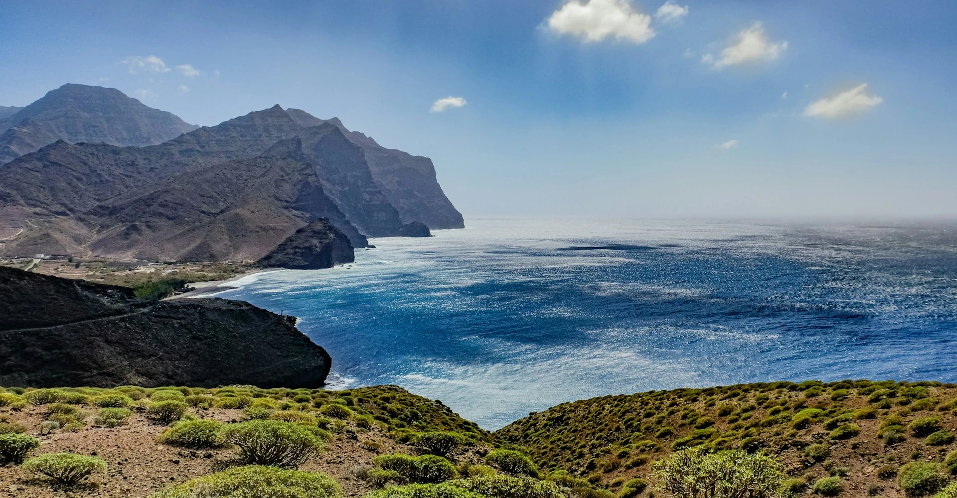 Western cliffs of Gran Canaria with Playa de la Aldea seen far away and the ocean extending far beyond the horizon