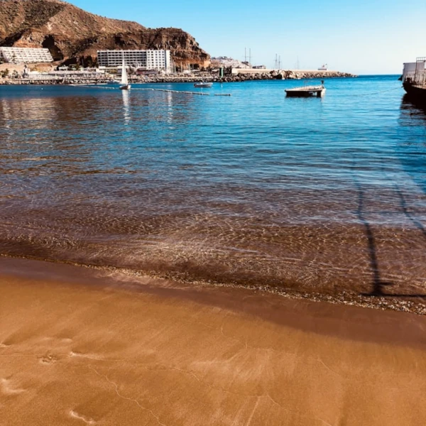 A golden sand beach with very calm water, and hotels and resorts on the other side of the shore