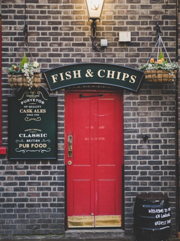 An authentic pub with a bright red door offering Fish and Chips