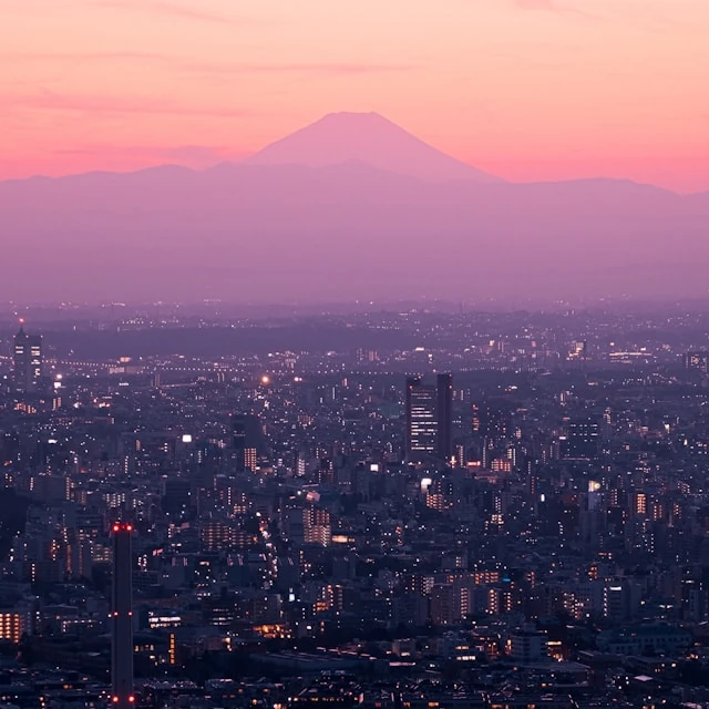 Vista aérea de Tokio al atardecer, con la silueta del monte Fuji visible en la lejanía.