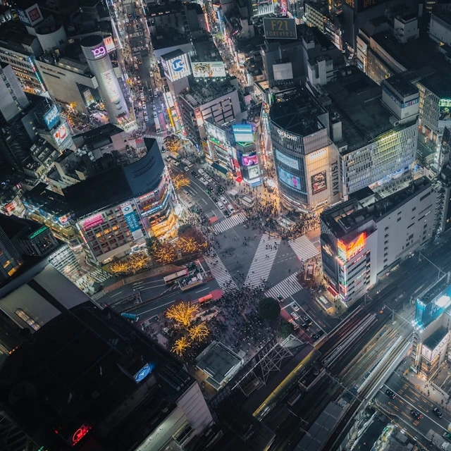 Vista aérea del cruce de Shibuya en Tokio por la noche, con gente que empieza a cruzar.