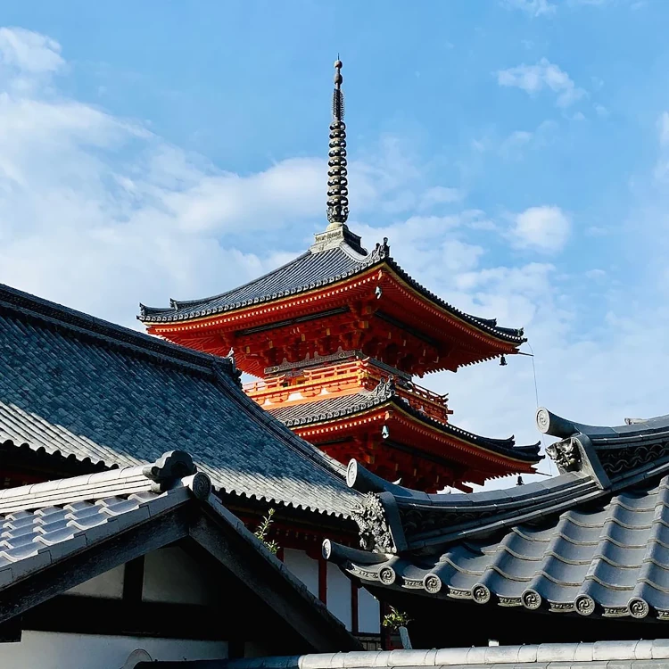 A serene view of the iconic Kiyomizu-dera Temple pagoda under a clear blue sky in Kyoto, Japan.