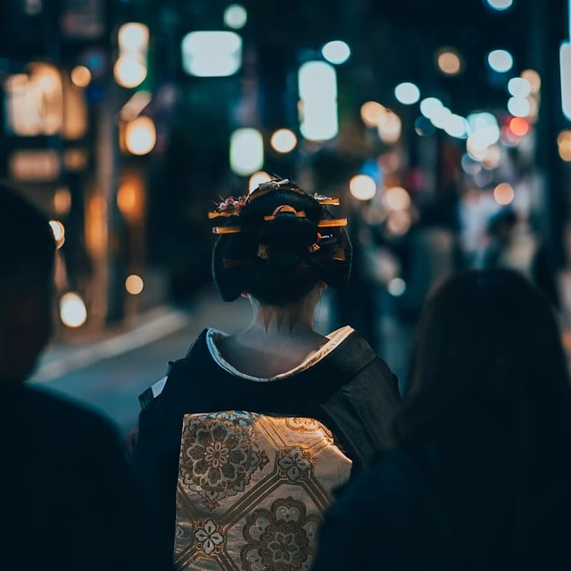 A person walking with a traditional japanese kimono and a traditional hair style.