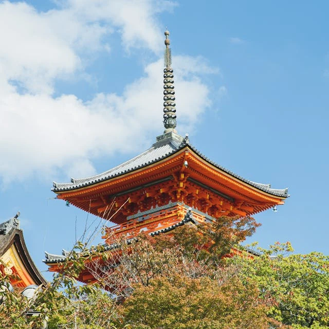 Stunning view of the iconic pagoda at Kiyomizu Temple with lush greenery and a vivid sky in Kyoto, Japan