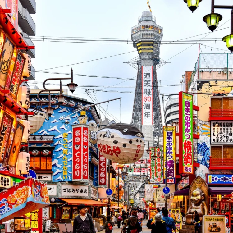 The bustling streets of Osaka with a clear view of the iconic Tsūtenkaku Tower, showcasing vibrant urban culture.