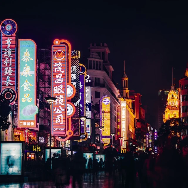 A busy street, lined with neon signs and lights at night