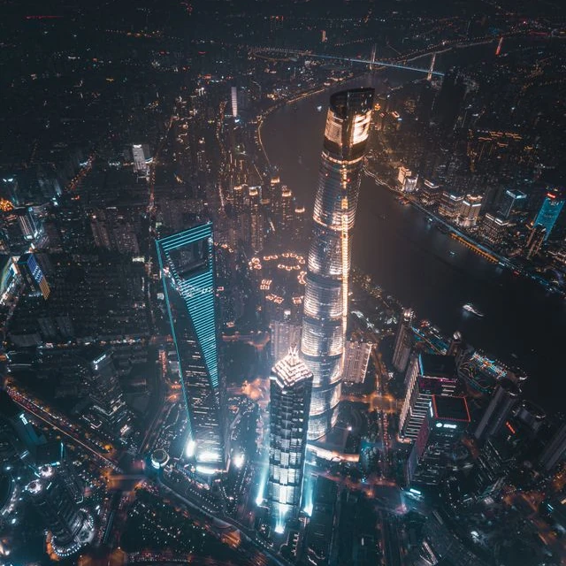 Shanghai's famous and iconic towers seen from above at night, with the city lit up at their feet
