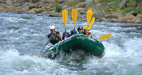 A group of people riding on the back of a raft down a river