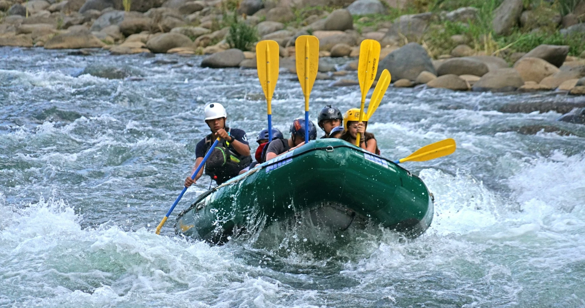 A group of people riding on the back of a raft down a river