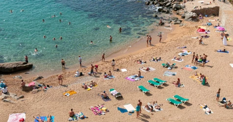 Golden sand beach in Costa Brava with turquoise waters and people enjoying a sunny summer day