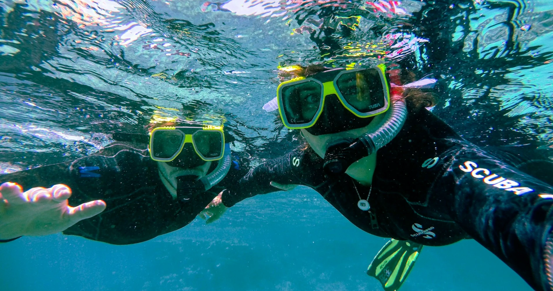 Two people snorkeling in the clear blue Caribbean waters of Roatán, Honduras