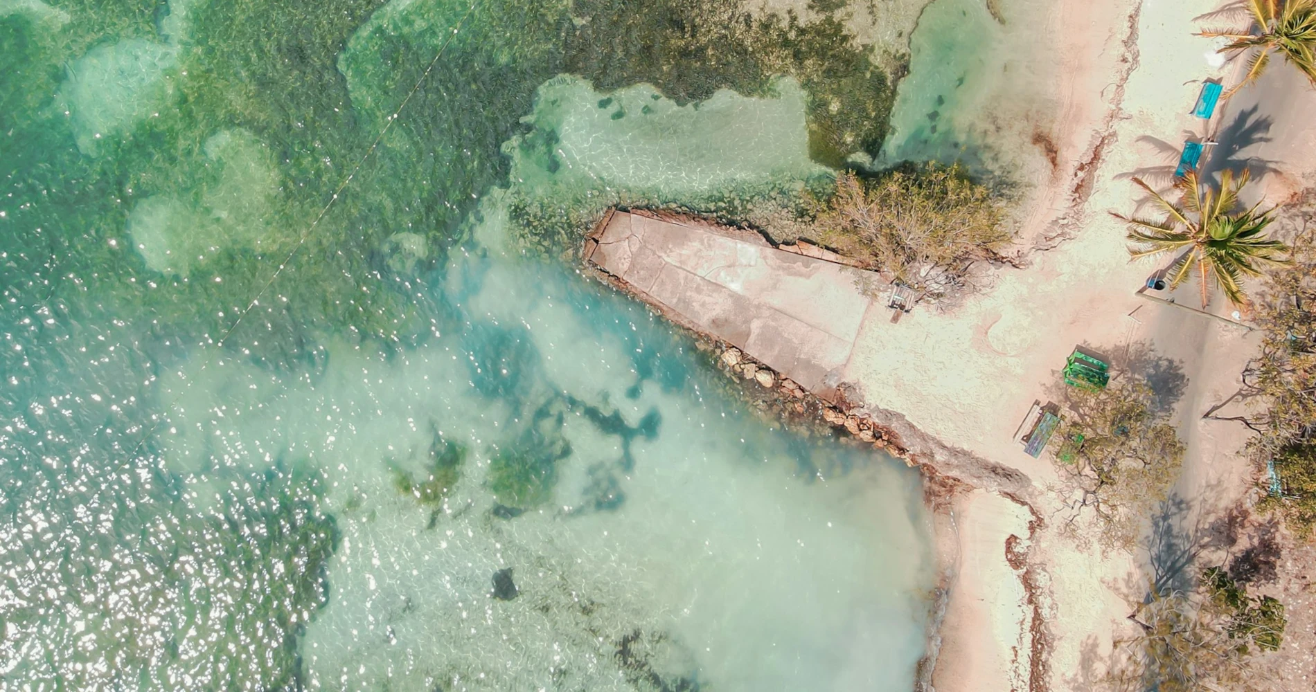 Tropical beach with white sands and clear blue waters from above