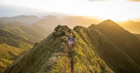 A women hiking at the top of a mountain during a beautiful sunset