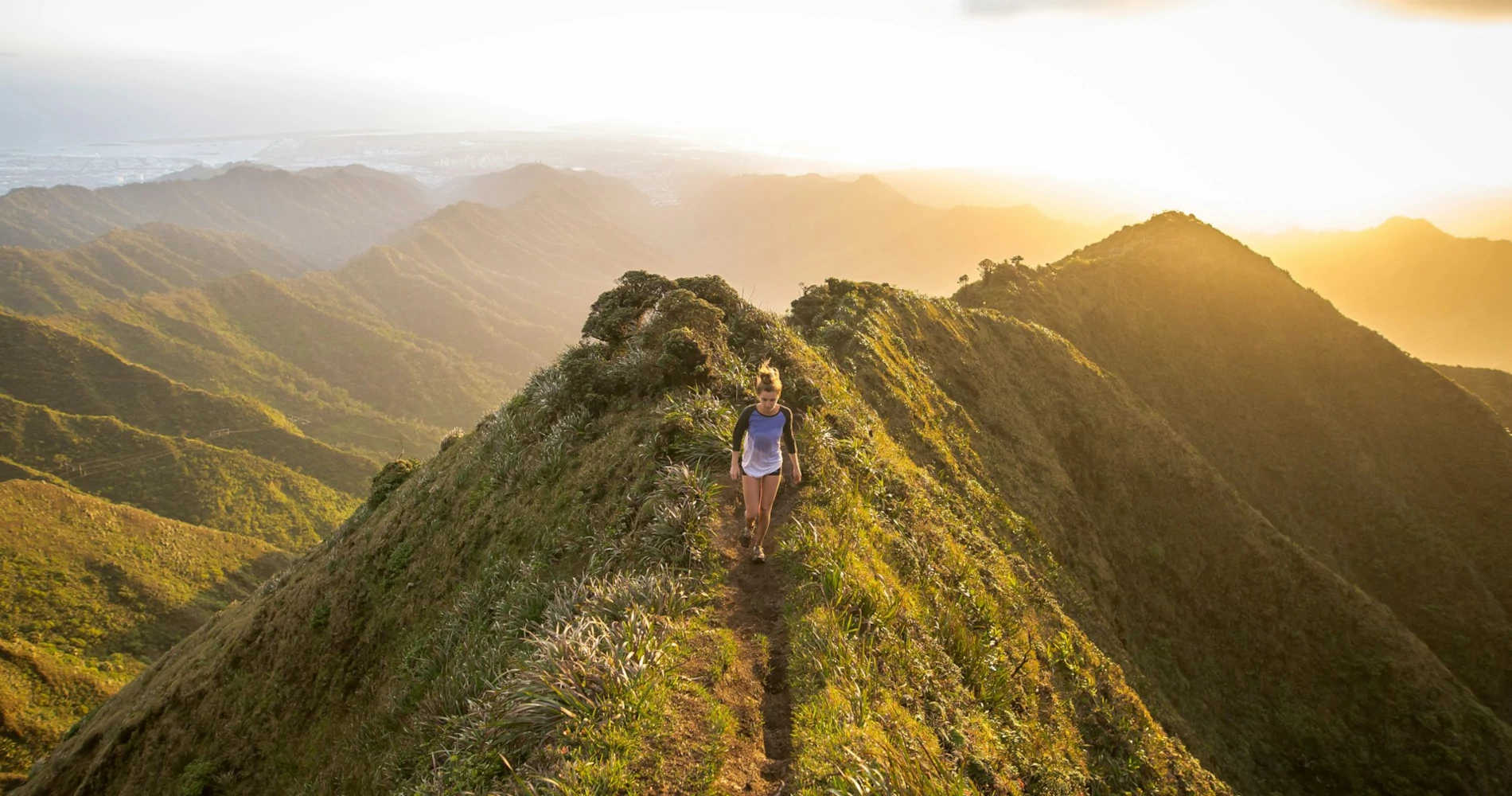 Una mujer caminando en la cima de una montaña durante una hermosa puesta de sol