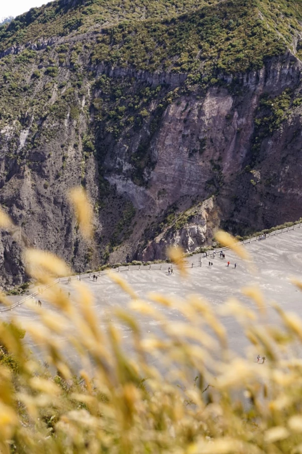 Descubre el Parque Nacional Volcán Irazú Gente a lo lejos caminando por un sendero rodeado de acantilados y montañas.